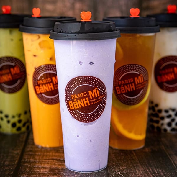 Five Paris Bánh Mì boba drinks in various colors, including purple, orange, and green.