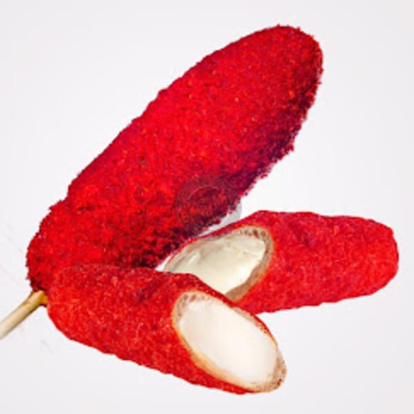 Three bright red, breaded corn dogs with creamy white filling, one on a stick.